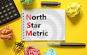 NSM north star metric symbol. Concept words NSM north star metric on white note on a beautiful yellow background. Calculator and