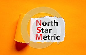 NSM north star metric symbol. Concept words NSM north star metric on white paper on a beautiful orange background. Business and