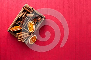 ntage box with spices - cinnamone, slices of dried orange, anise on textured paper background. photo