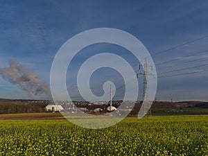 Nuclear power plant in Neckarwestheim, Germany, located at the bank of Neckar river, with power line, pylon and field.