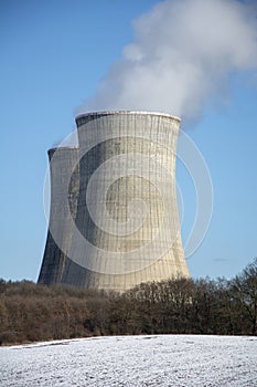 Jadrová elektráreň v zime. Chladiace veže. Modrá obloha v pozadí. Sneh na poľnohospodárskom poli