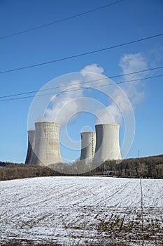 Jaderná elektrárna v zimě. Chladicí věže. Modrá obloha v pozadí. Sníh na zemědělském poli