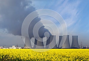 Nuclear power plant with yellow field and clouds.