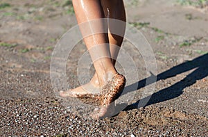 Nude female legs sea sand