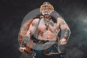 Nude and muscular viking with armed with hatchet and knife