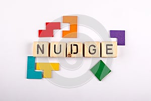NUDGE. Wooden alphabet letters and colorful figures on a white background photo