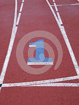 Number 1 painted on running track racing lane with white lines clearly marking lanes