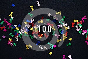 Number 100 and sparkly party hats glitter