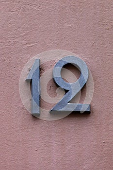 Number 12 vintage metal house number on pink wall