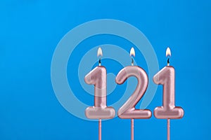 Number 121 - Burning anniversary candle on blue foamy background