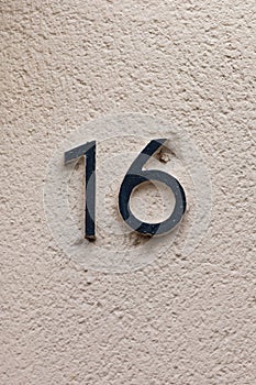 Number 16 black house number on white wall