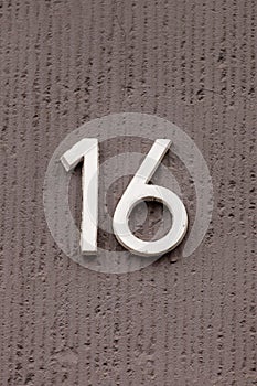 Number 16 white house number on gray wall