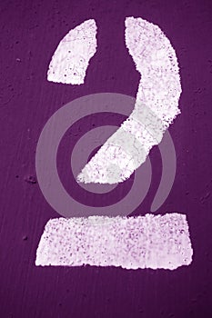 Number 2 in stencil on metal wall in purple tone