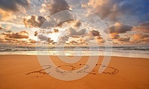 Number 2017 written on seashore sand at sunrise. Concept of upcoming new year and passing of time