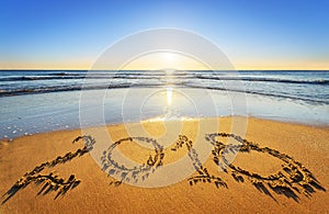 Number 2018 written on seashore sand at sunrise. Concept of upcoming new year and passing of time.