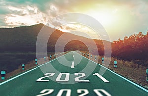 Number 2021 on highway road with high mountains and bright sunlight to Goals success. Concept New year 2021