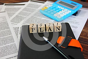 The number 2021 with letter plan on wooden cube on dairy , business planing . business concept