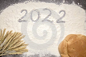 Number 2022 with ears of wheat and loaves of bread on flour. New Year and Christmas concept