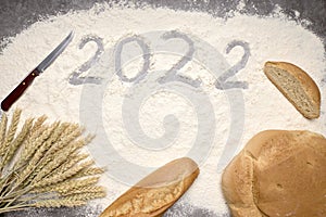 Number 2022 with ears of wheat and loaves of bread on flour. New Year and Christmas concept
