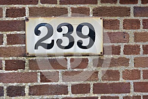 Number 239 on red brick wall, black numerals