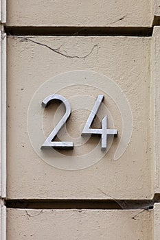 Number 24 metal house number on beige wall
