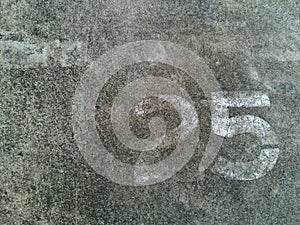 Number 25 Twenty five in white painted on the gray concrete wall or surface of street with copy space