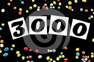Number 3000 with multicolored candy around on black background