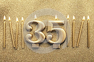 Number 35 gold celebration candle on a glitter background