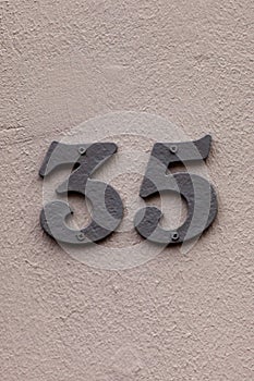 Number 35 vintage metal house number on gray wall