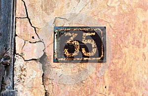 Number 35 on wall sign, rusty and weathered.