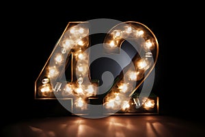 Number 42 cover crafted from elegant golden numbers with chic lamps on a dark background.