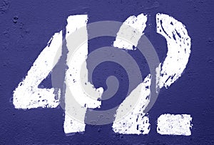 Number 42 in stencil on rusty metal wall in blue tone