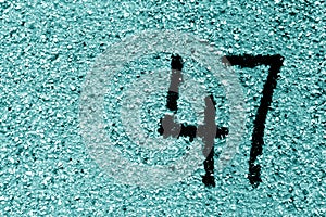 Number 47 on cement wall in stencil in cyan tone