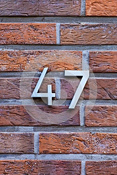 Number 47 metal house number on brick wall