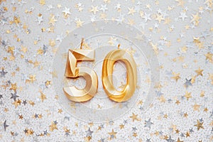 Number 50 fifty golden celebration birthday candle on Festive Background.