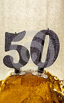 Number 50 happy birthday celebration candle. Candles on a homemade cake. Silver background