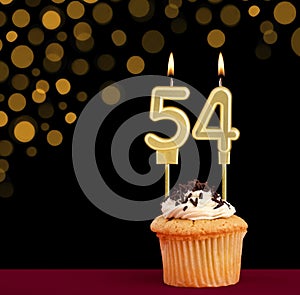 Number 54 birthday candle - Cupcake on black background with out of focus lights