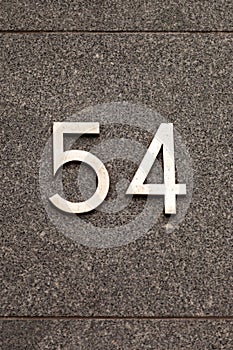 Number 54 vintage metal house number on granite wall