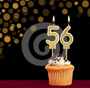 Number 56 birthday candle - Cupcake on black background with out of focus lights