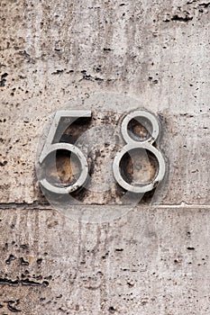 Number 58 vintage metal house number on white stone wall