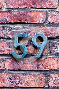 Number 59 metal house number on brick wall