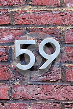 Number 59 metal house number on brick wall