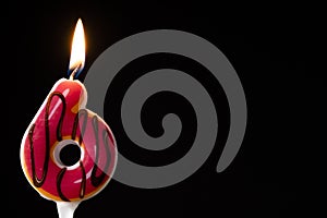 Number 6 birthday celebration donut candle against a black background