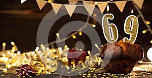 Number 69 golden festive burning candles in a cake, wooden holiday background. sixty nine years since the birth. the