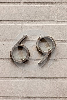 Number 69 metal house number on white brick wall