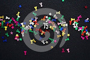 Number 75 with shiny party hat star glitter on black background