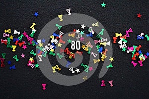 Number 80 with shiny party hat star glitter on black background