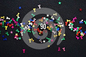 Number 90 amidst sparkly metallic confetti party hats and stars 