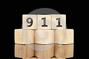 The number 911 on wooden cubes on a glossy black background