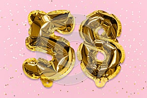 The number of the balloon made of golden foil, the number fifty-eight on a pink background with sequins.